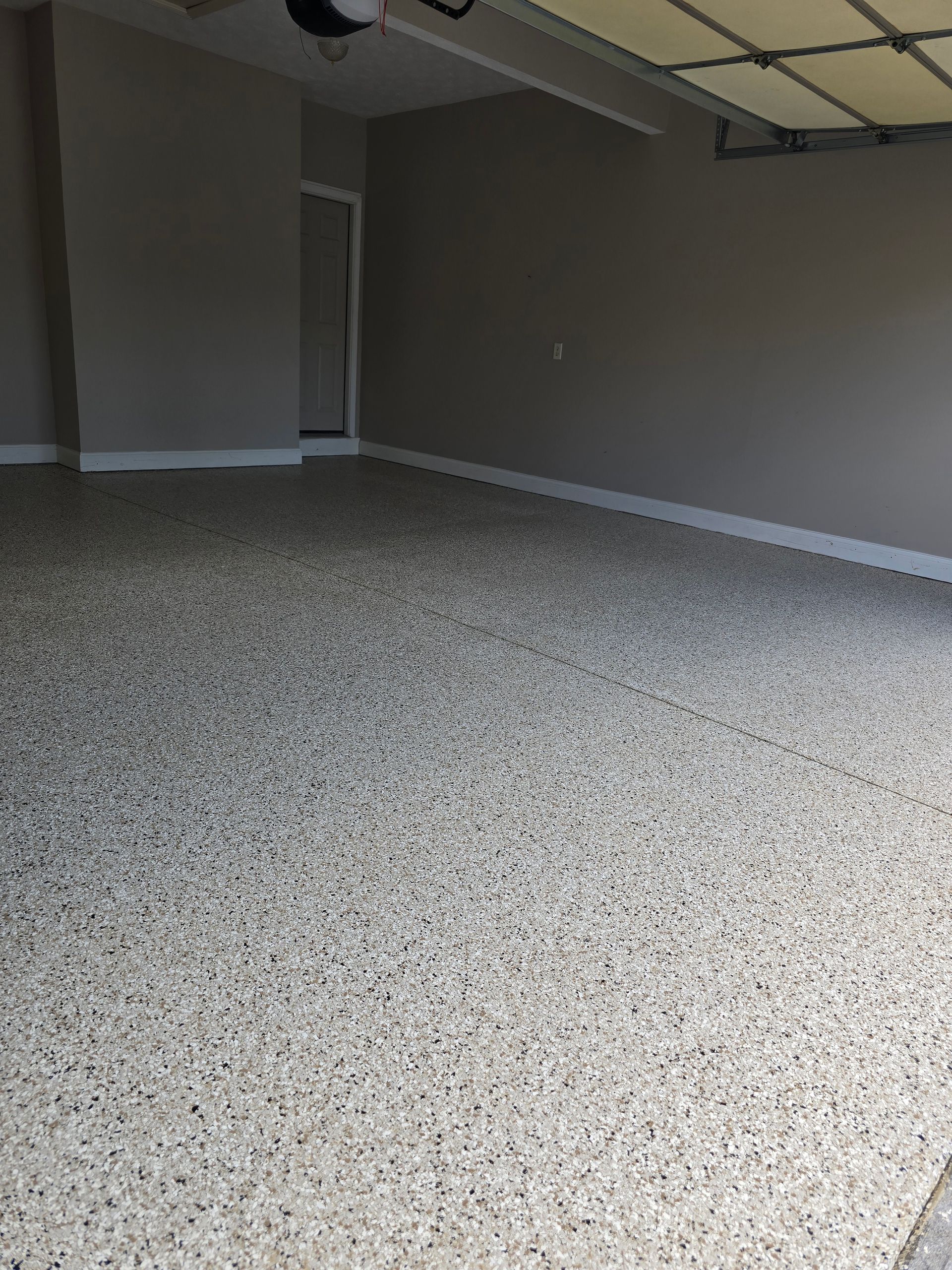 Empty carpeted room with beige walls and a doorway, lit by soft indoor light
