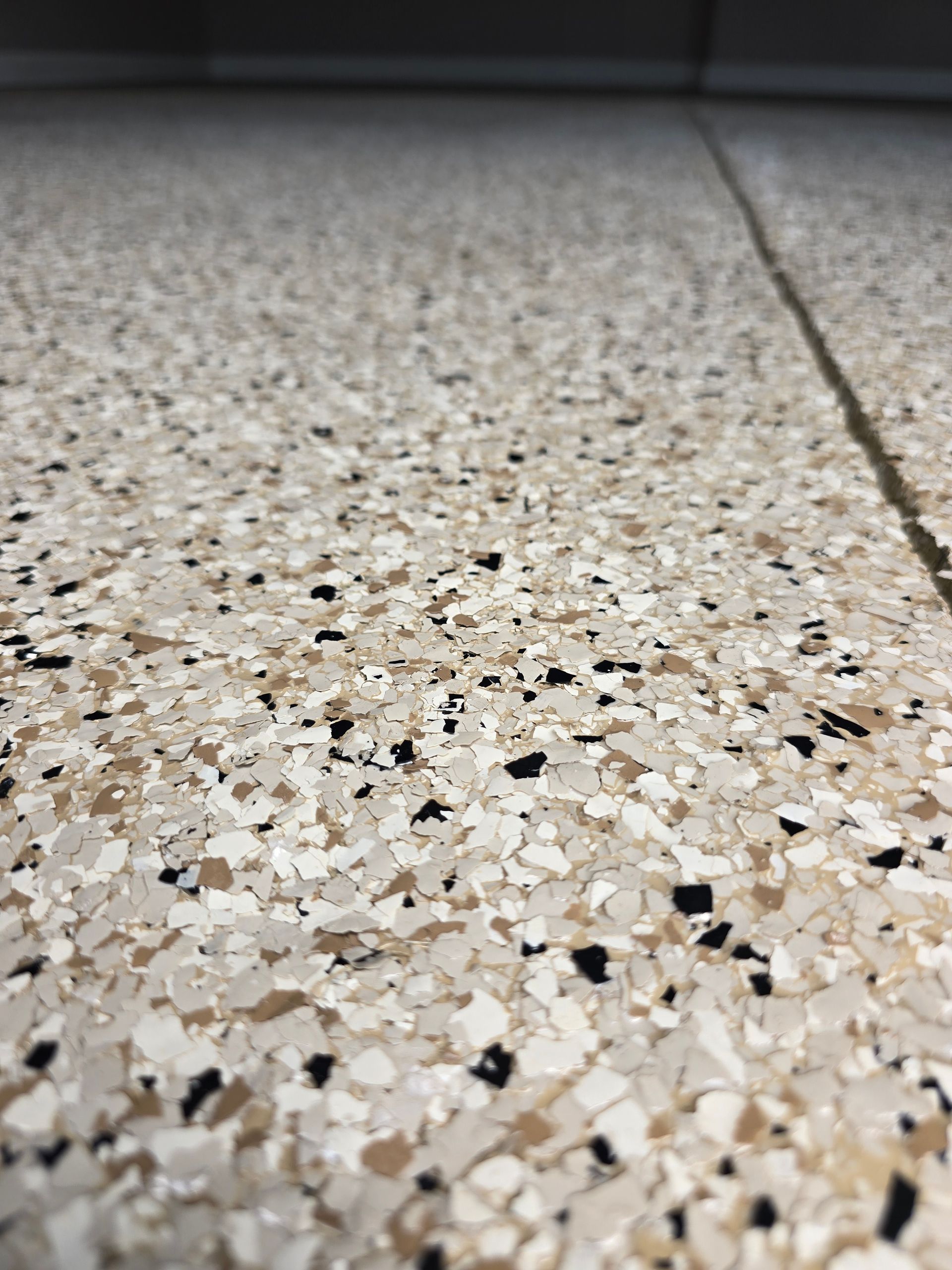 Close-up of a speckled terrazzo floor with a blurred wall in the background