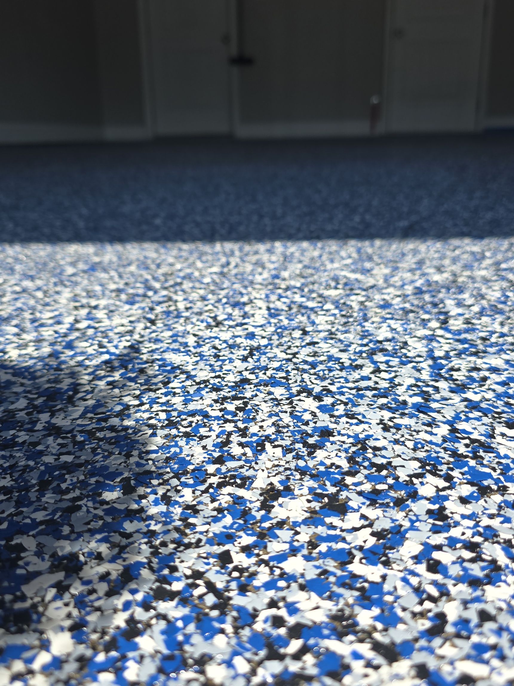 Blue and white speckled floor with sunlight and shadow across a room