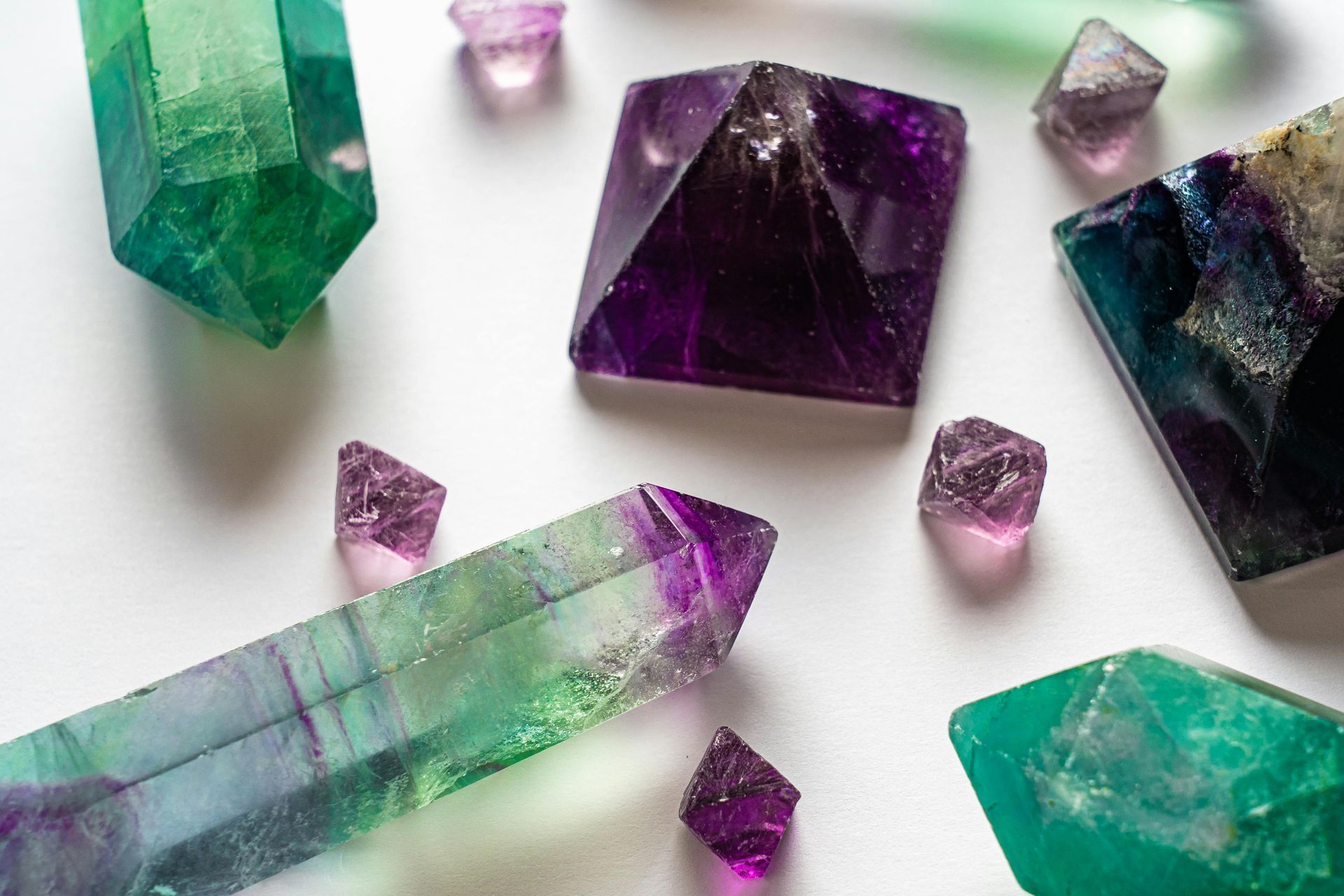Cristaux de fluorite verts, violets et transparents de tailles variées sur fond blanc.