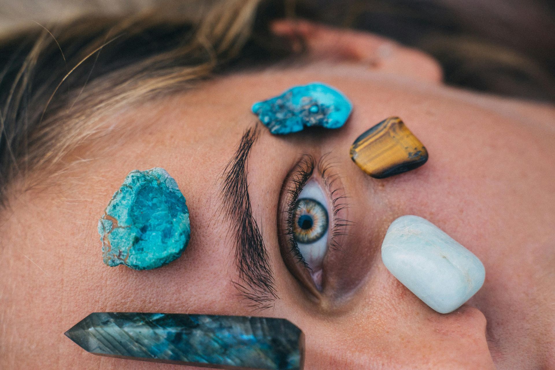 Un œil entouré de turquoise et d'autres cristaux sur le front d'une personne.
