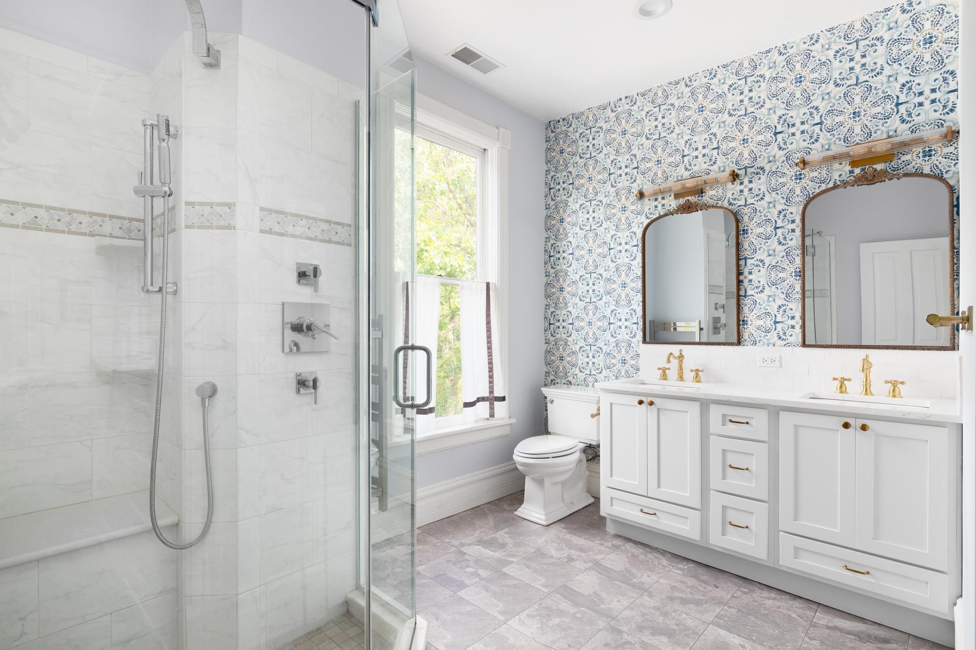 A bathroom with two sinks , a toilet , and a walk in shower.