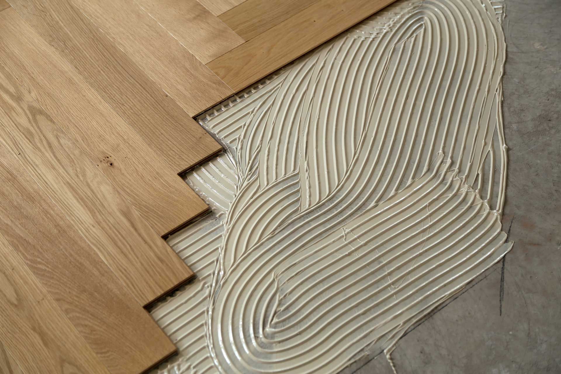 A person is laying a tile floor with a hammer.