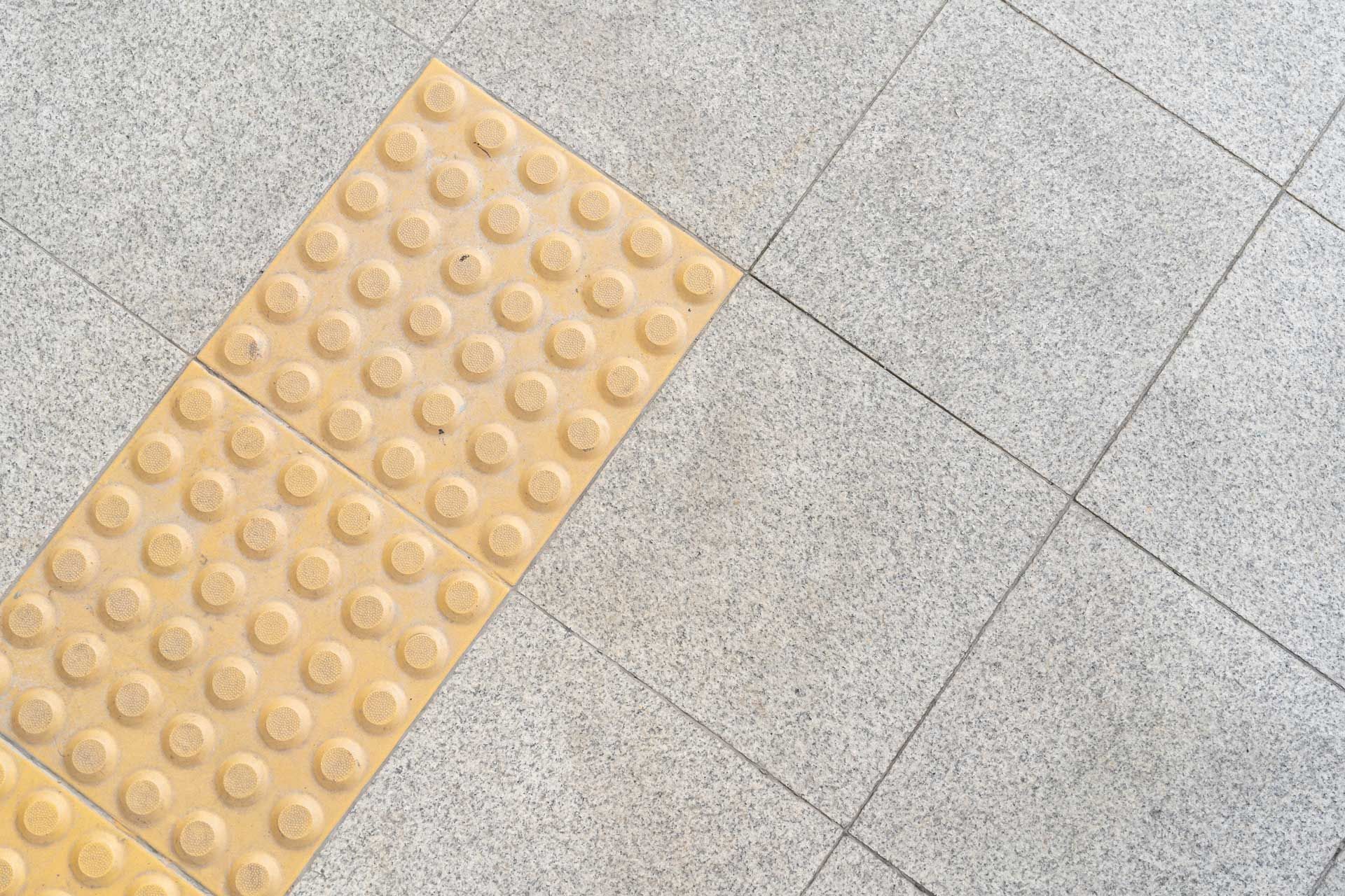 A row of yellow tiles on a gray tiled floor.