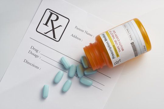 Prescription bottle spilled blue pills on a pharmacy form