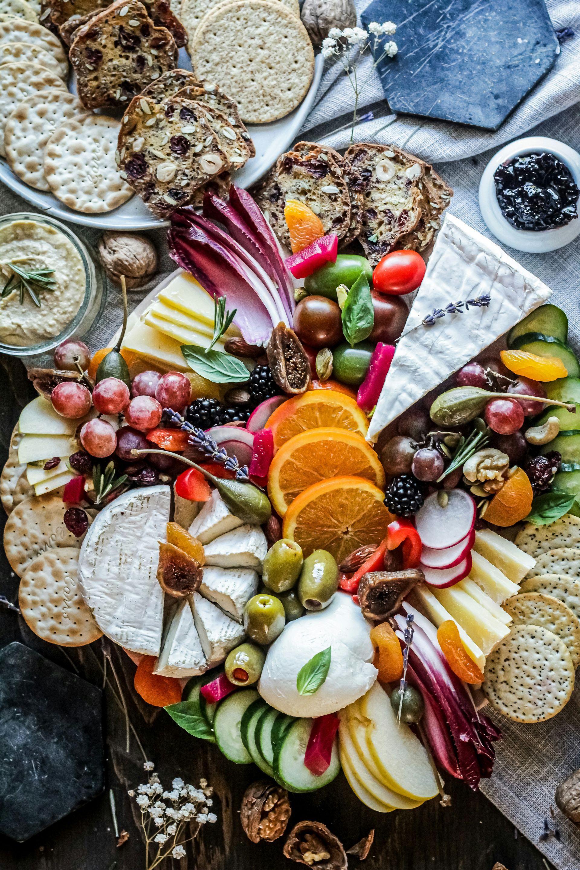 Planche de charcuterie colorée avec fruits, fromages, crackers, noix et pain sur une table rustique