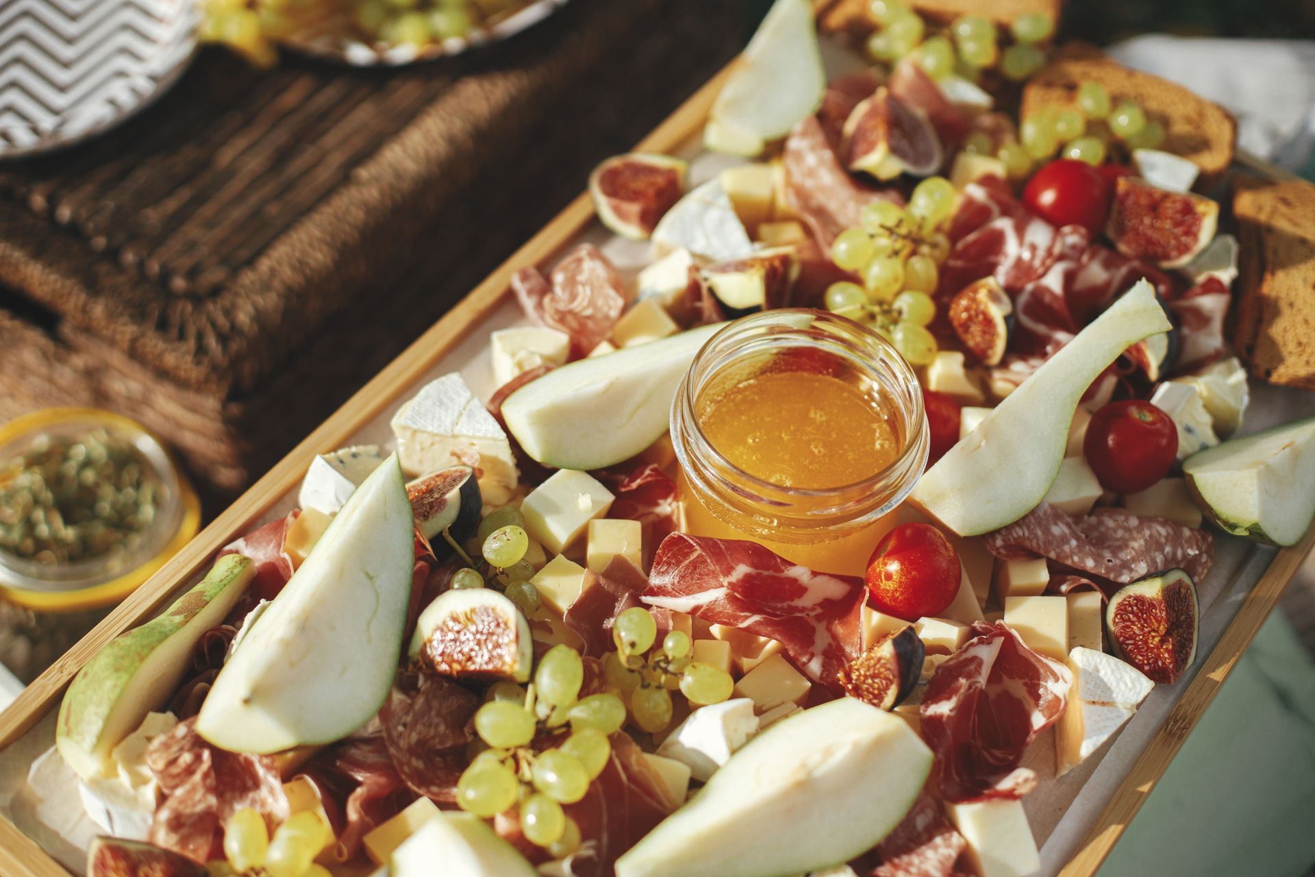 Plateau de charcuterie avec fromage, fruits, noix et miel dans un plateau en bois