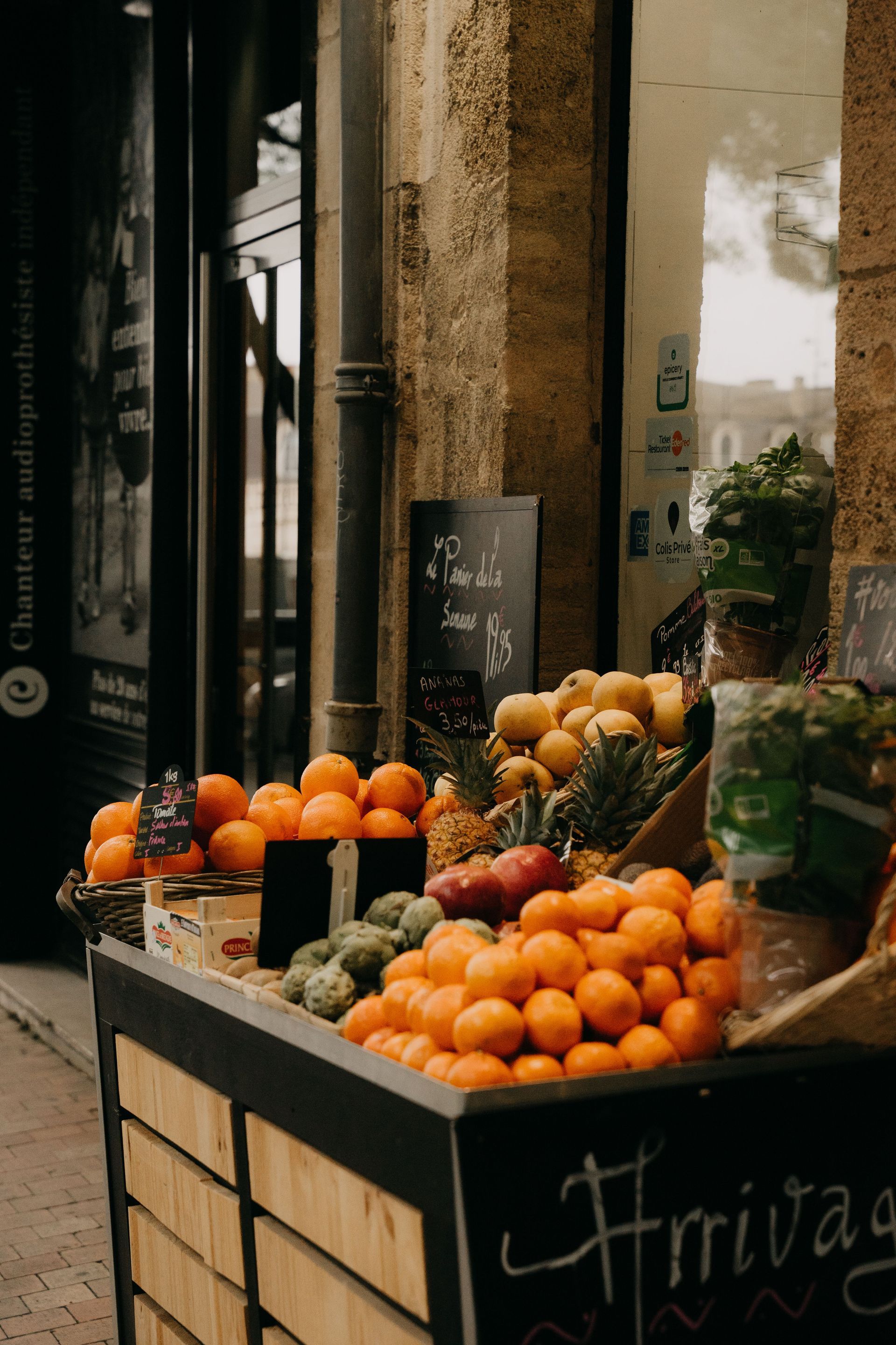 Étal de marché avec des caisses d'oranges et d'autres fruits devant une boutique