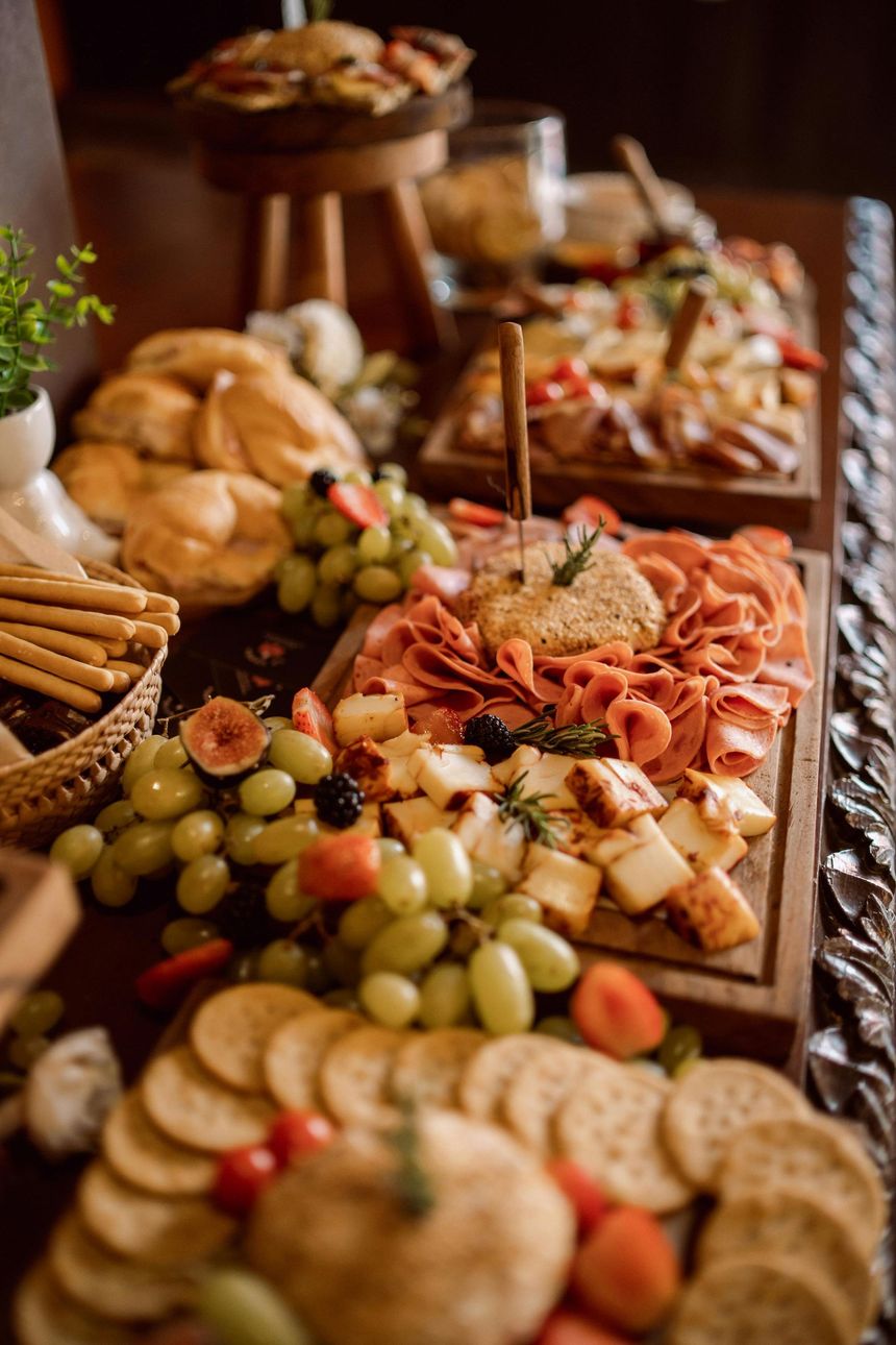 Planche de charcuterie avec raisins, crackers, fromage, viande et pain sur une table en bois