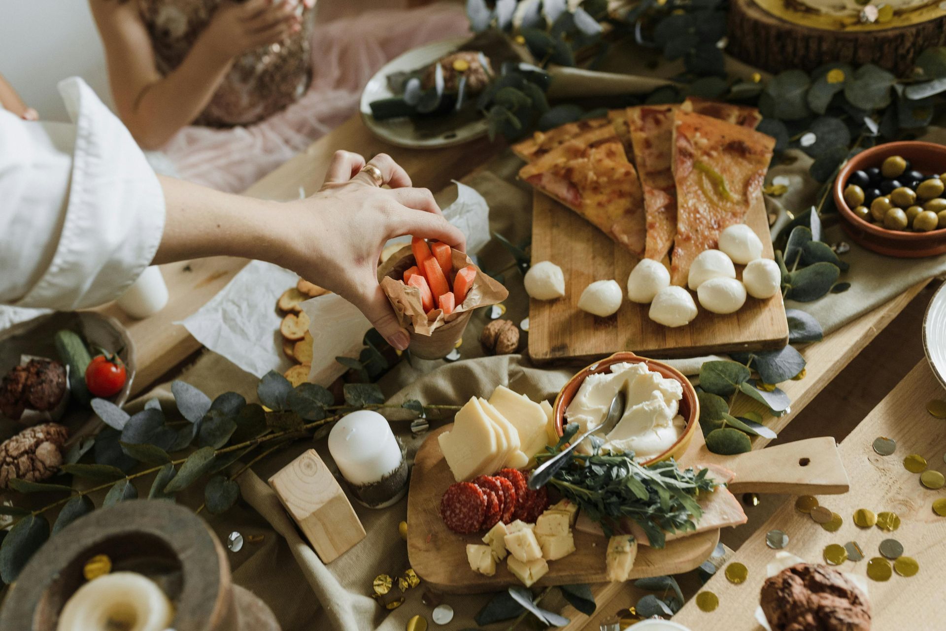 Des mains disposent des fraises sur une planche de charcuterie rustique avec du fromage, des olives et des figues.