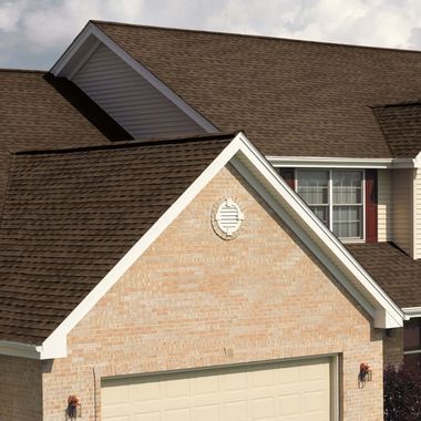 Suburban brick house with beige garage door and dark shingle roof