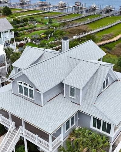 Gray beach house with metal roof beside raised garden beds and the waterfront