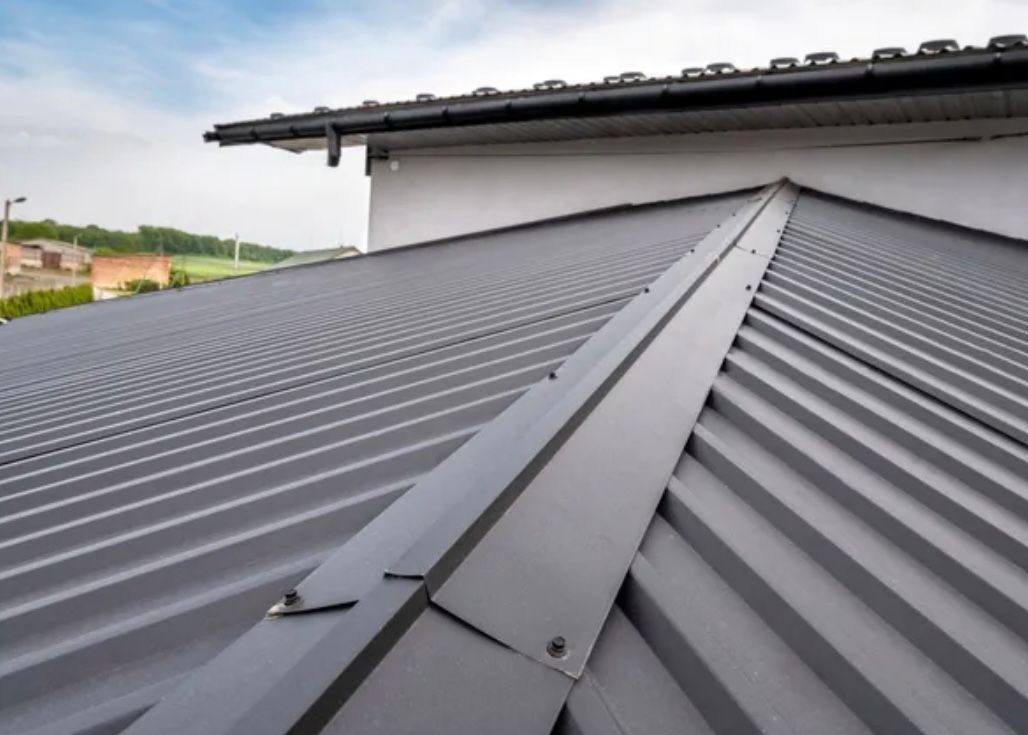 Gray metal roof with standing seam and corrugated panels on a building exterior