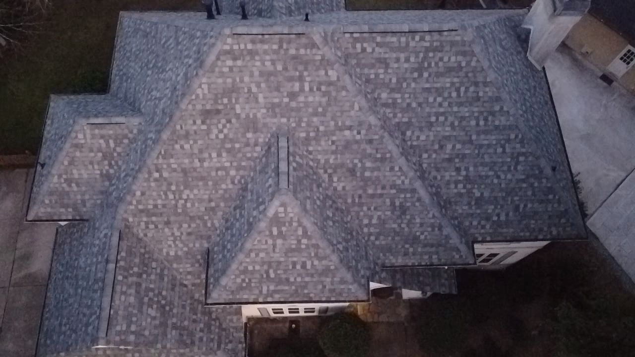 Aerial view of a gray-shingled house roof with multiple gables and a central dormer.