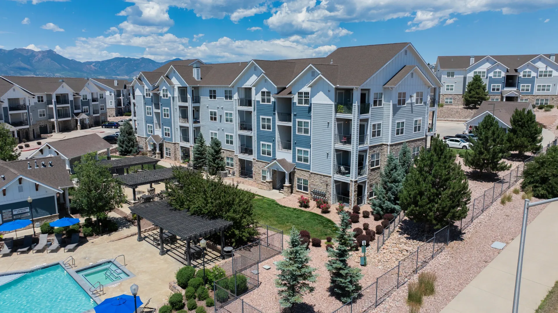 Exterior view of apartment buildings with a pool and hot tub area.