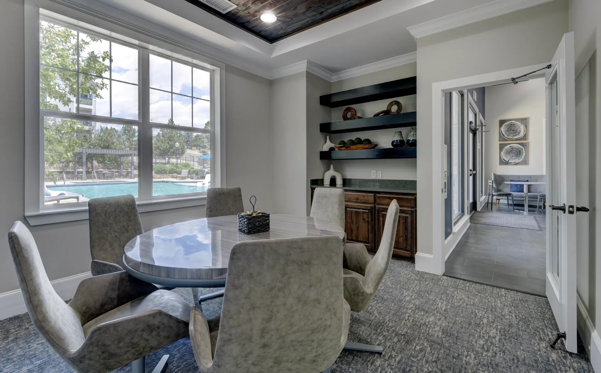 Interior seating area with a round table and chairs, overlooking an outdoor swimming pool.