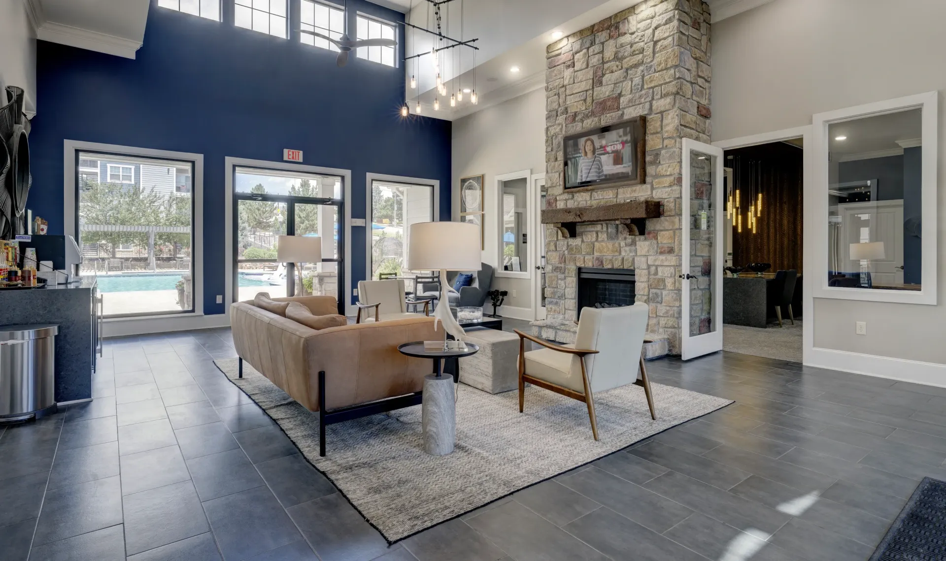 Clubhouse lounge area with a fireplace, comfortable seating, and view of the pool.