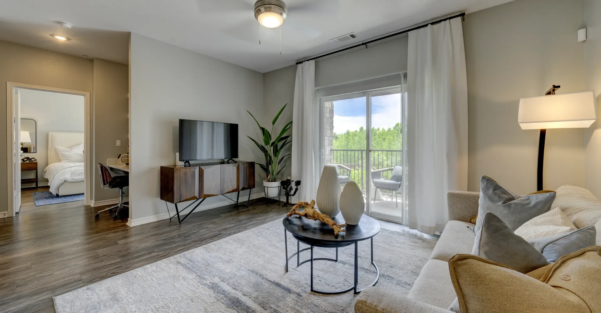 Living room with TV, sofa, and view of balcony.