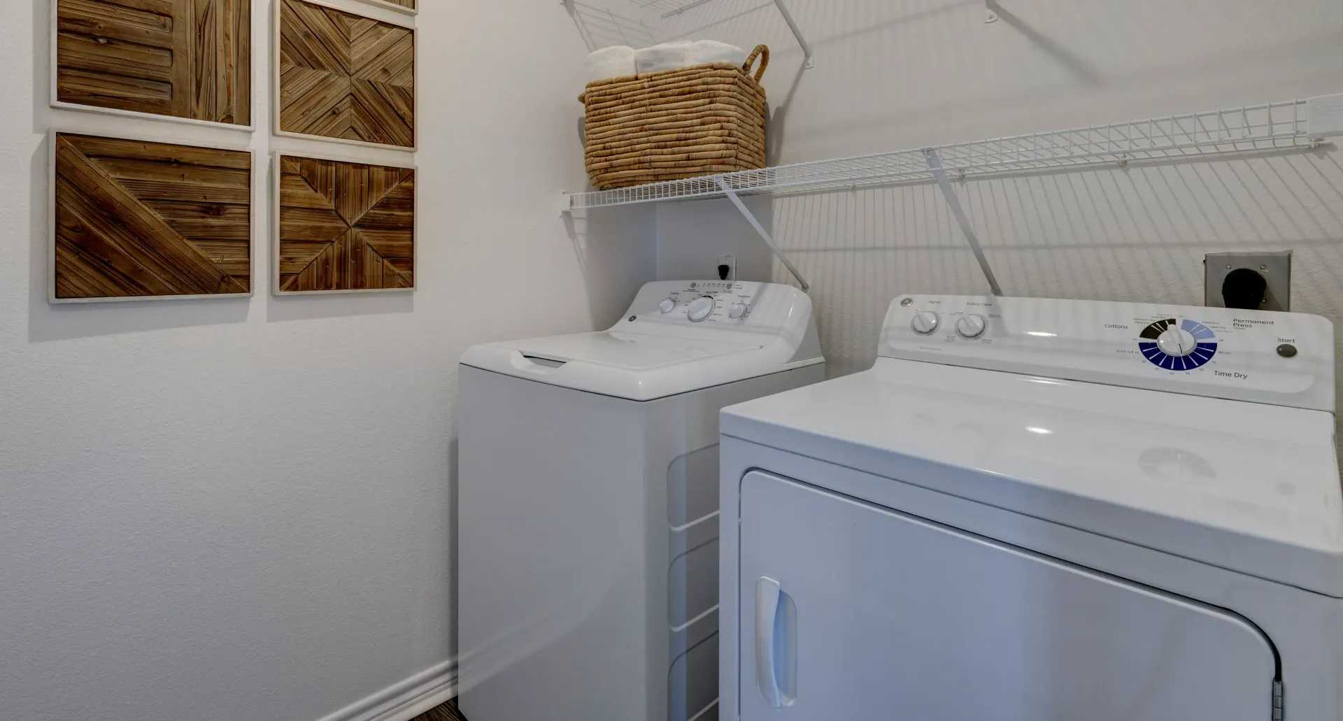 In-unit washer and dryer with decorative wood art above.