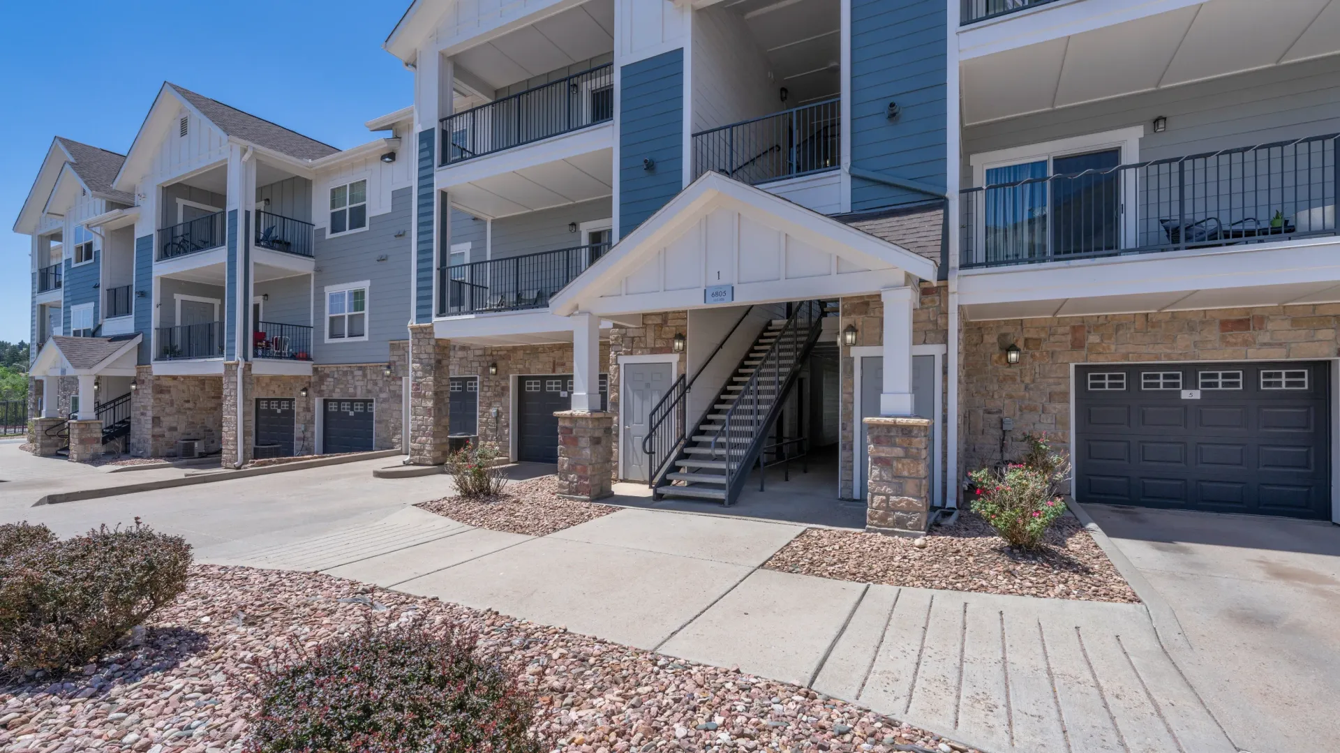 Exterior view of apartment buildings with attached garages and balconies.
