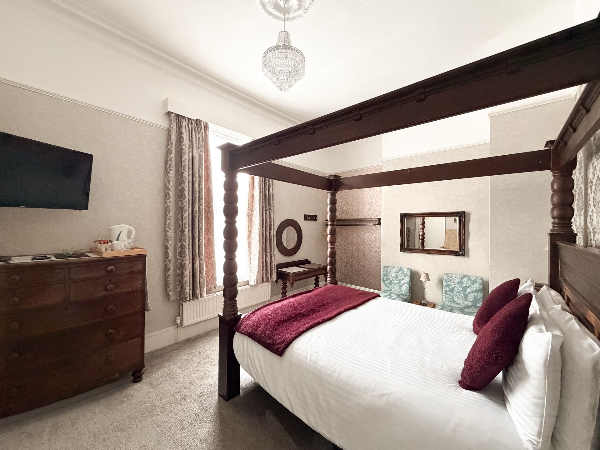 Bedroom with a four-poster bed, dark wood furniture, and a small TV.