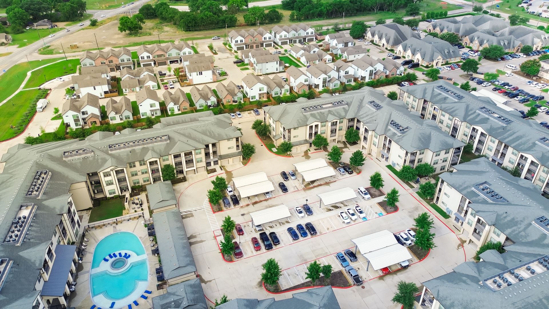 Aerial view of apartment complex with pool and townhouses, light-colored buildings. Aerial view of apartment complex with pool and townhouses, light-colored buildings.