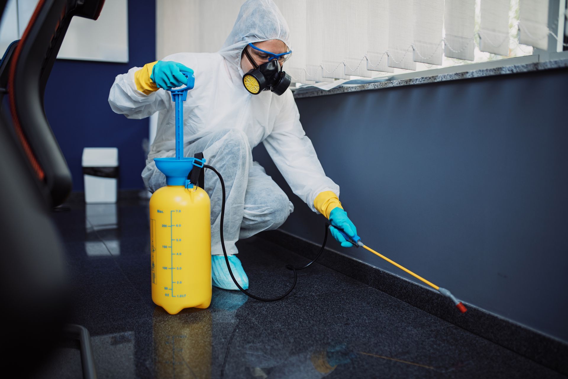 Person in hazmat suit spraying insecticide along a wall. Person in hazmat suit spraying insecticide along a wall.