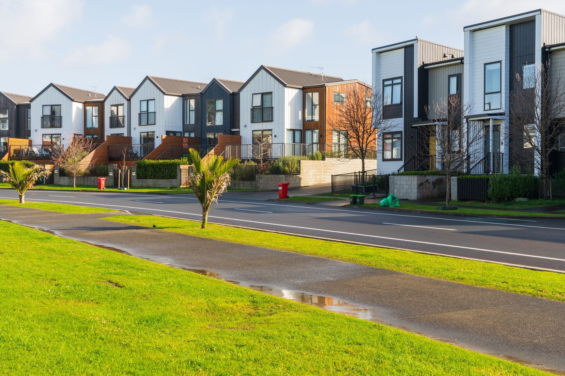 Row of modern houses with green lawns and a paved walkway. Row of modern houses with green lawns and a paved walkway.