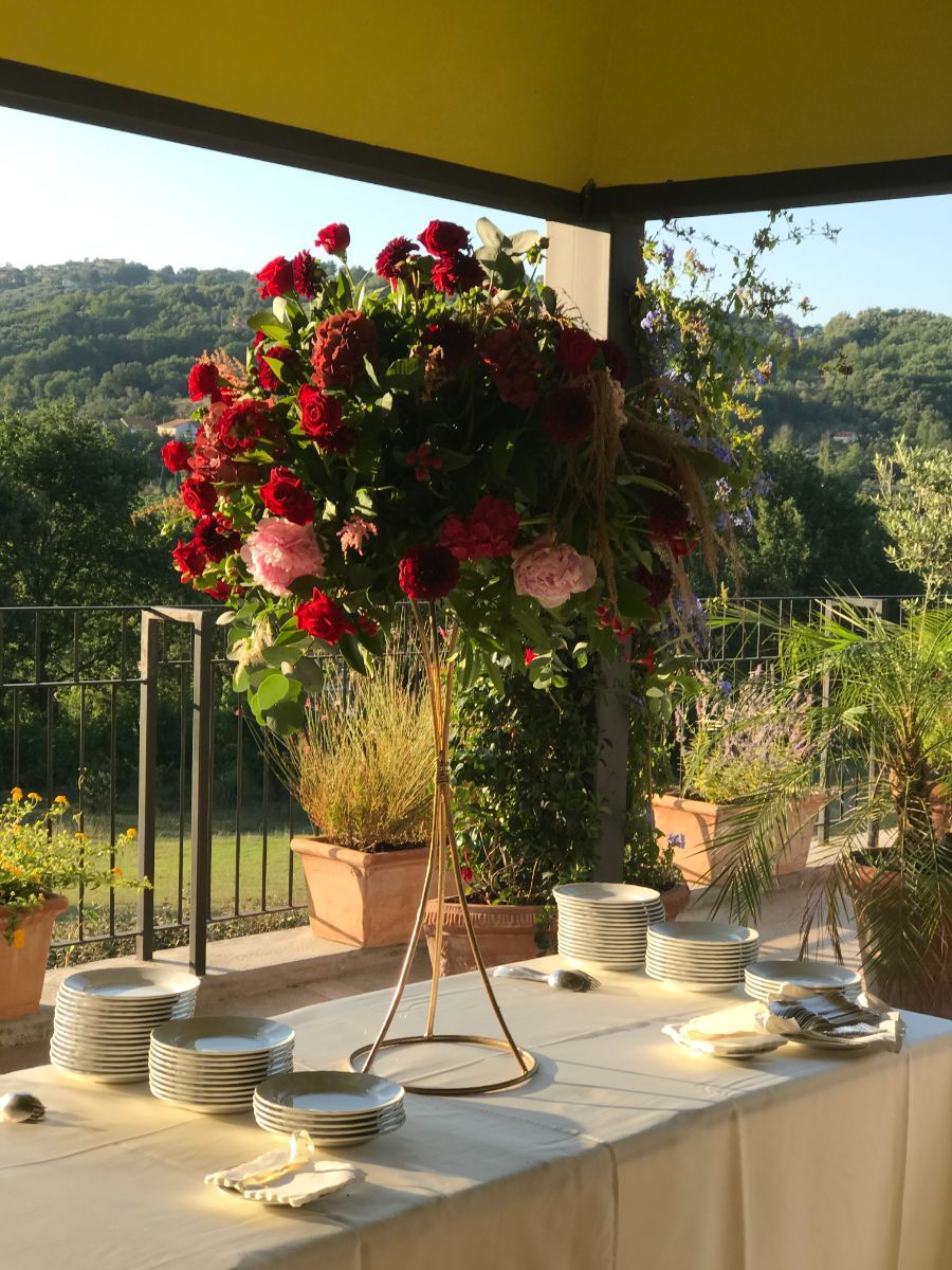 composizione floreale con rose rosse su portavaso dorato