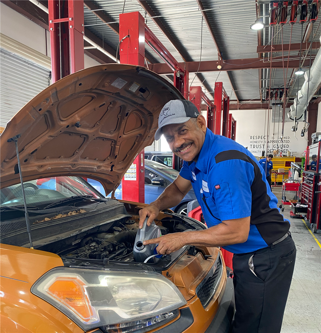 A man is working on a car in a garage with the hood open | Elite Auto Repair
