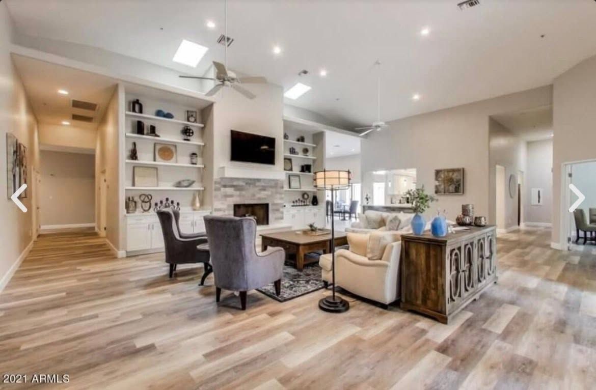 Bright open-concept living room with kitchen, fireplace, wood floors, and modern neutral decor