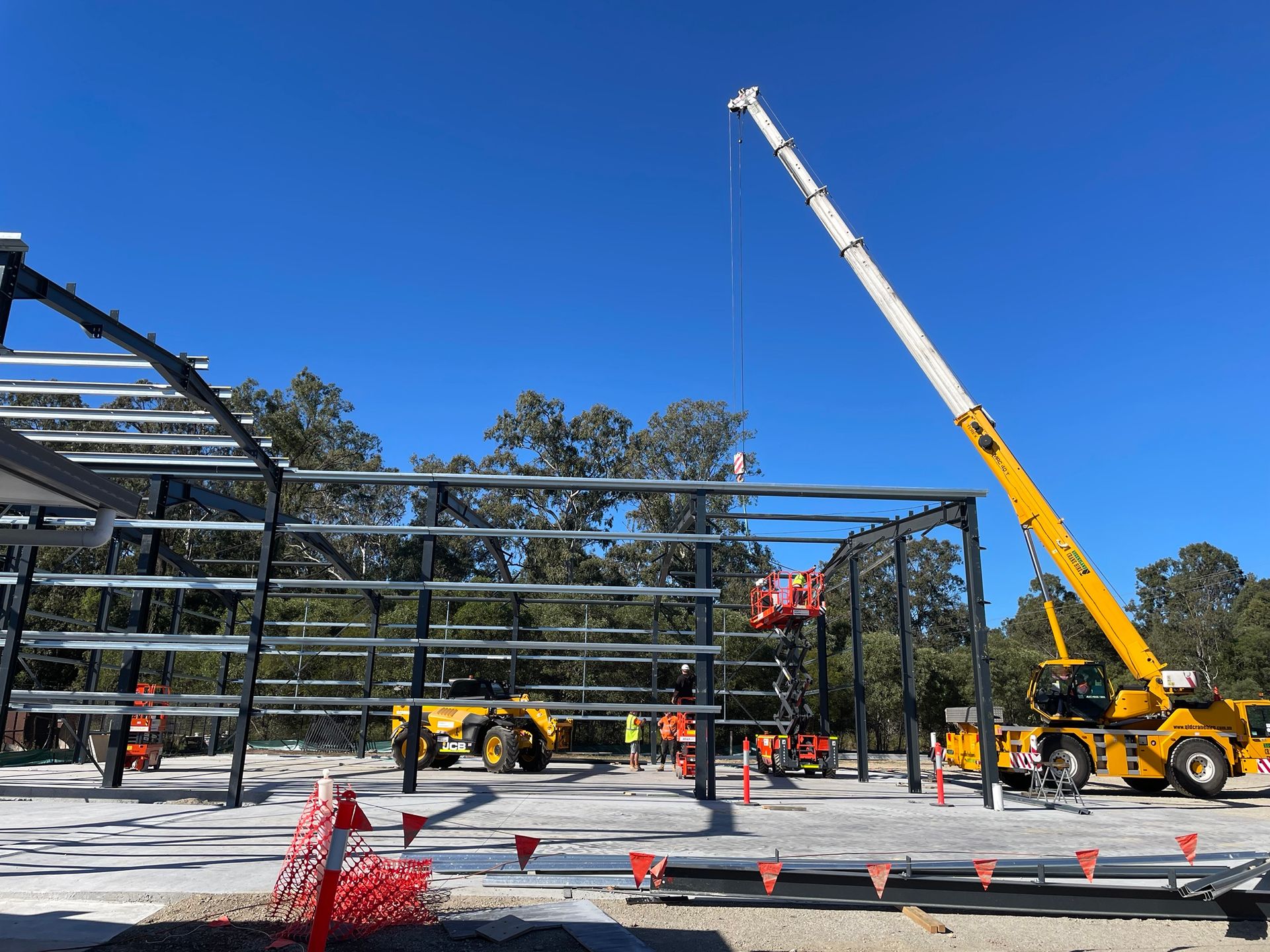 A large yellow crane is lifting a metal structure on a construction site.