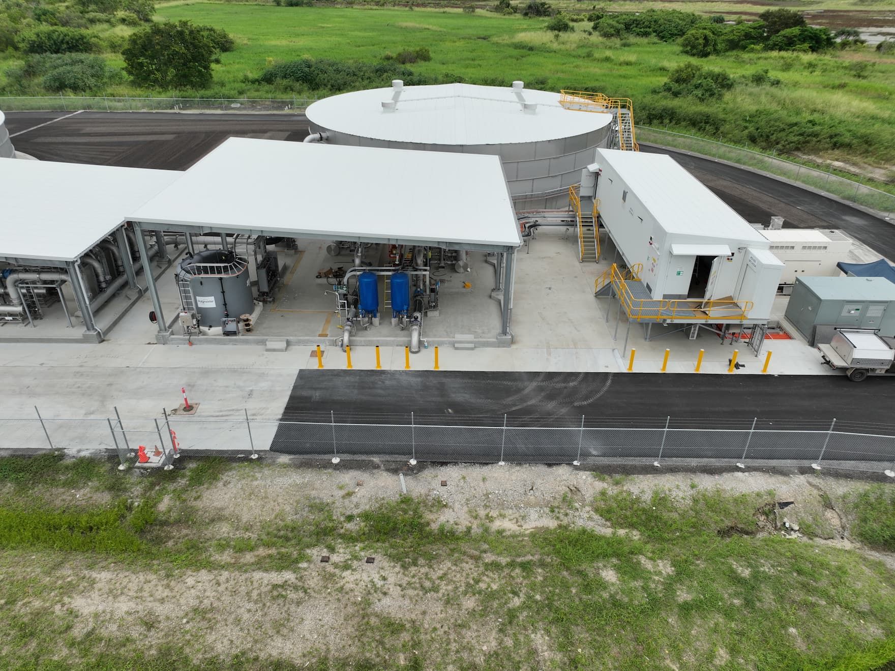 An aerial view of a large building with a white roof in the middle of a field.