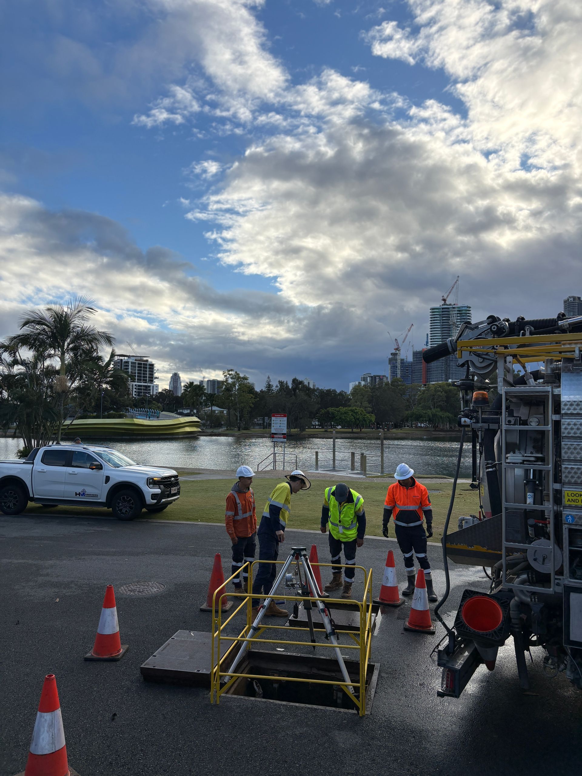 Workers in safety gear at a Sewer Pump Station with trucks and a scaffold under a cloudy sky
