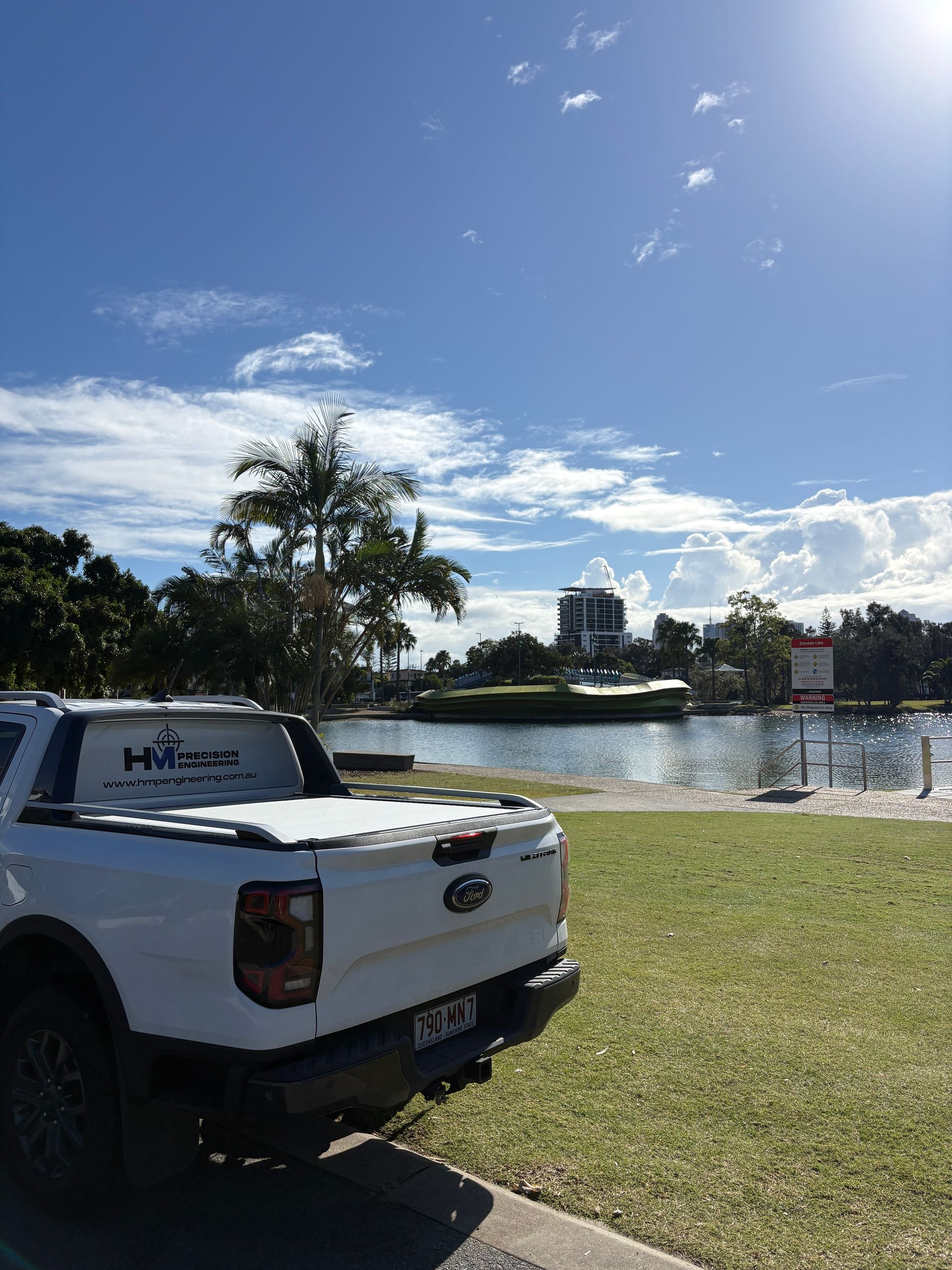 White pickup truck parked on grass beside a lake under a blue sky with clouds during a condition assessment inspection