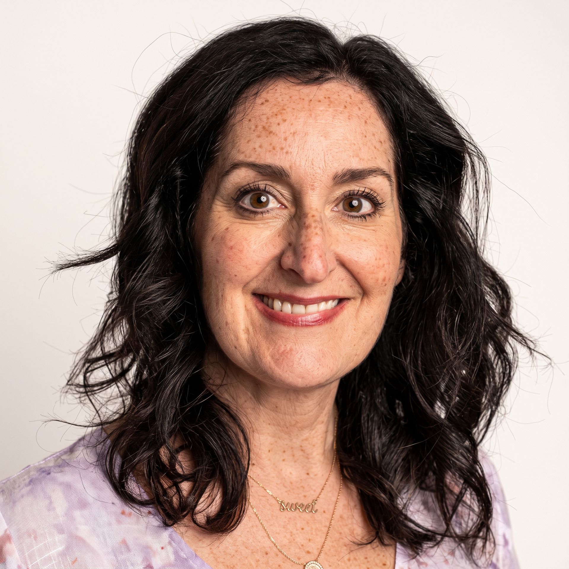 Smiling woman in a light lavender floral top against a plain white background
