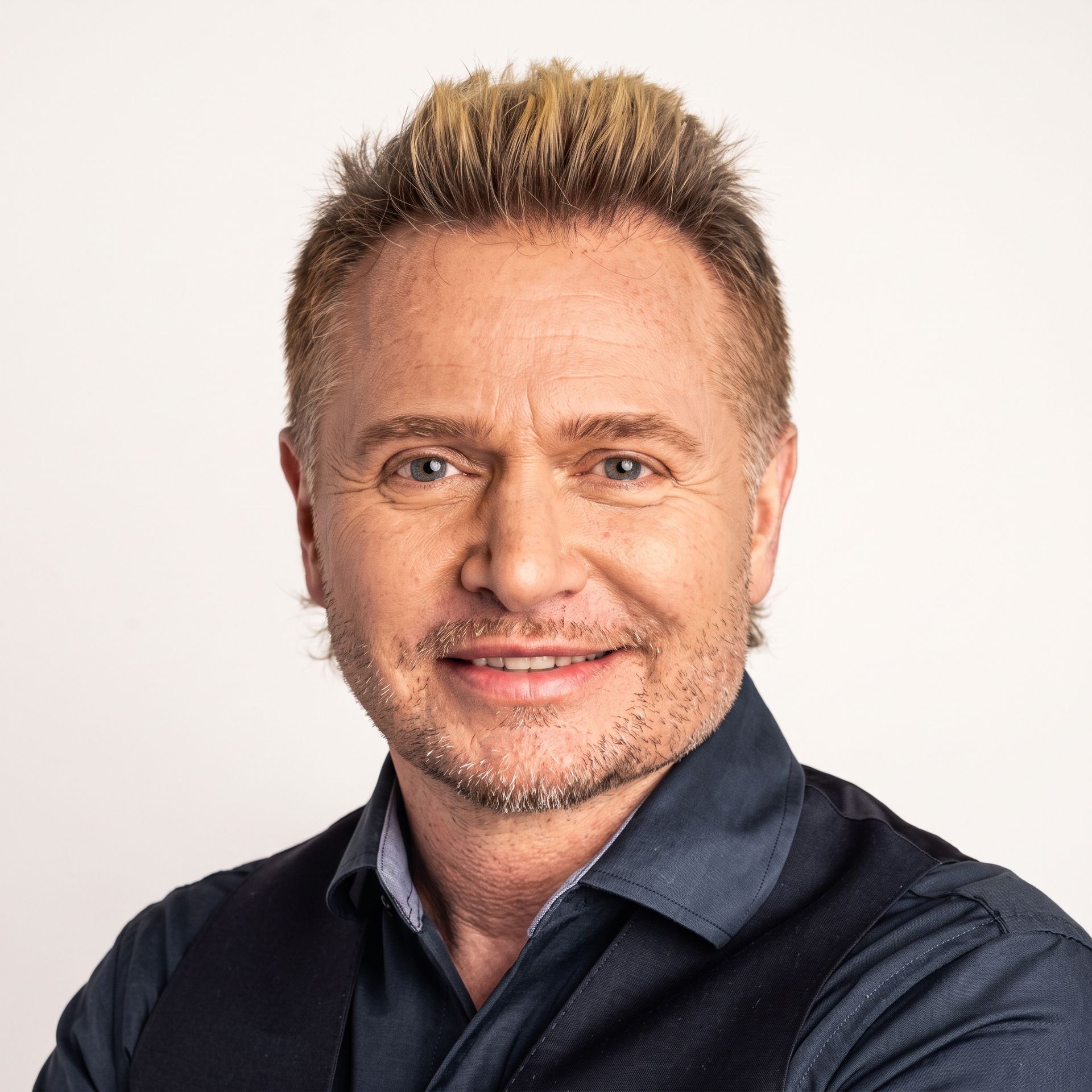 Portrait of a smiling man in a dark shirt against a light background