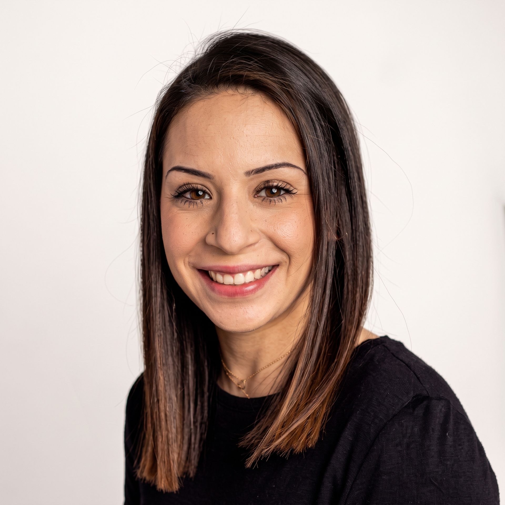 Smiling woman with straight dark hair wearing a black top against a white background
