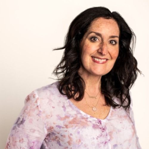 Smiling woman in a light pink floral blouse against a white background