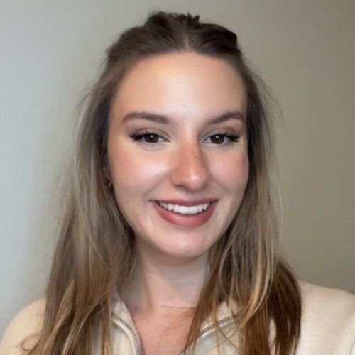 Smiling woman with long brown hair against a plain gray background
