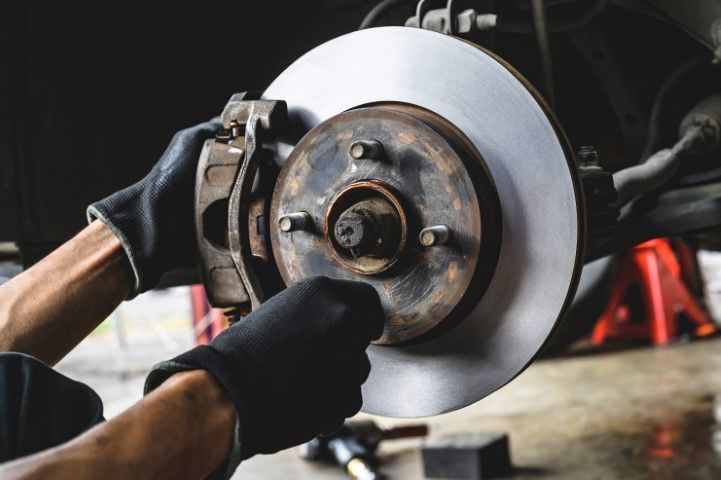 Mechanic using a tool to remove a car brake rotor in a workshop