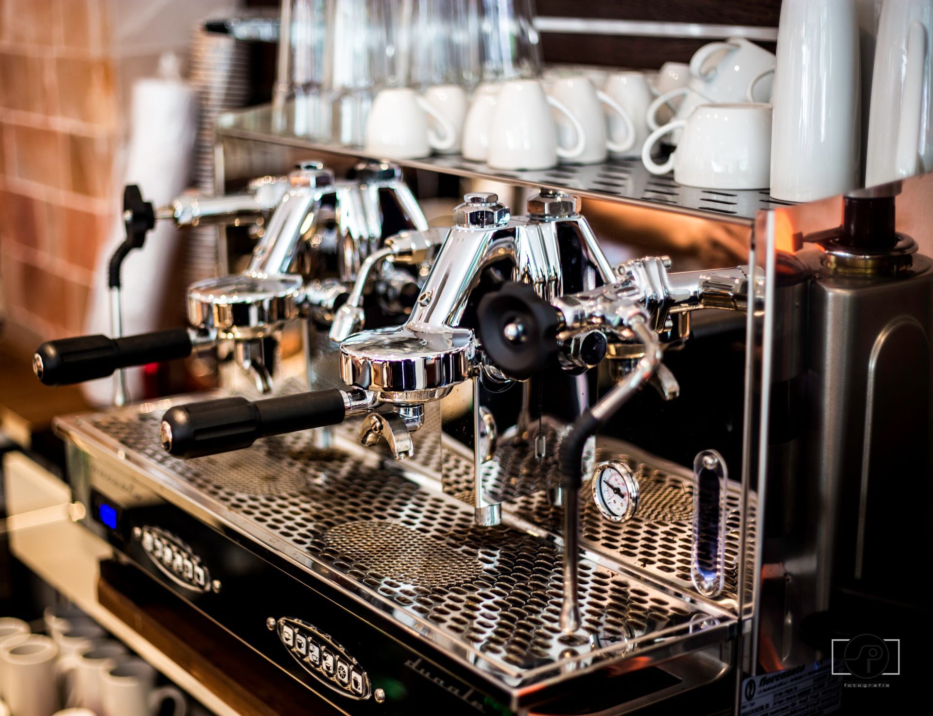 Auf einer Theke steht neben einem Regal mit Tassen eine Kaffeemaschine.