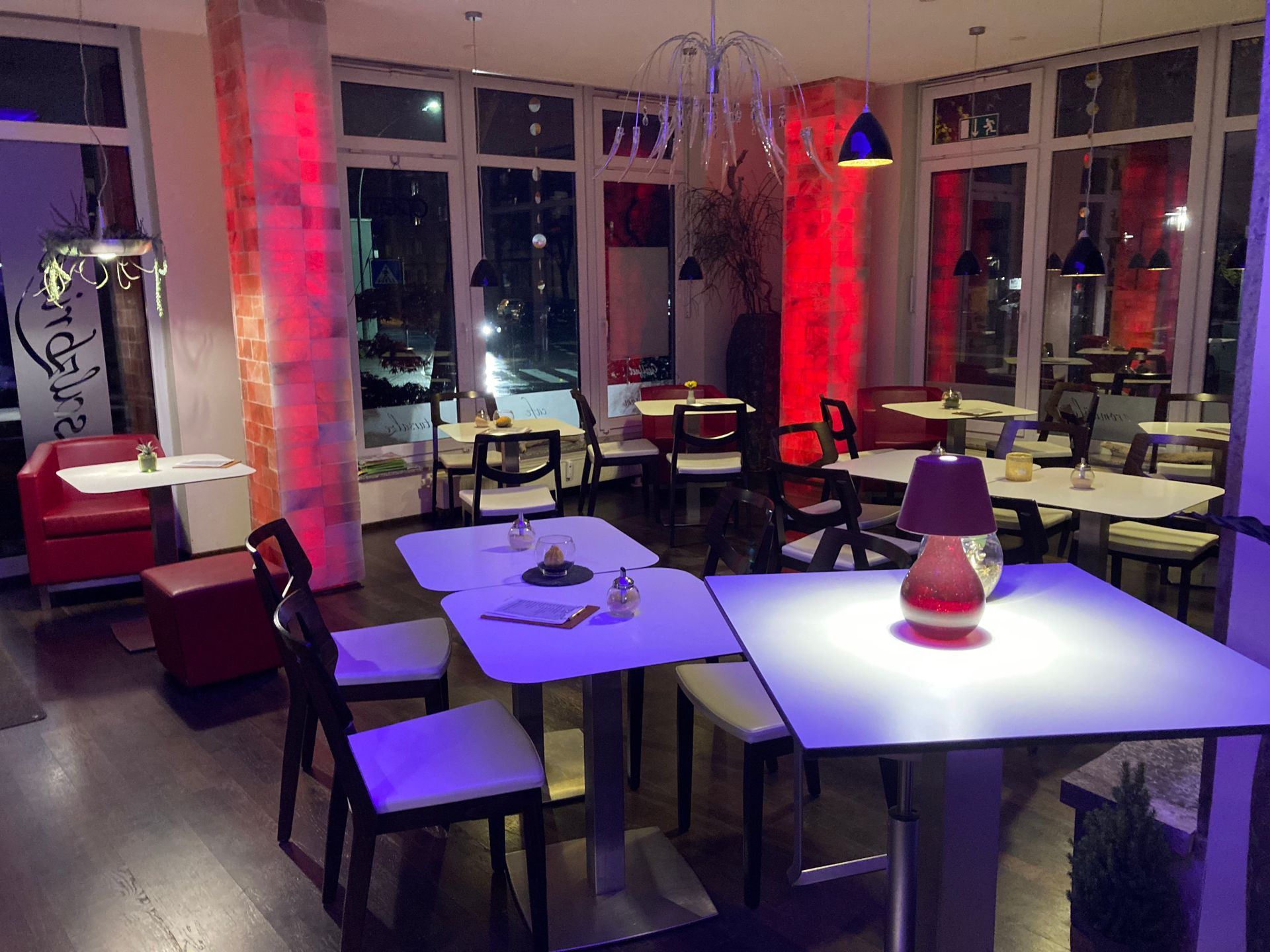 Ein Restaurant mit Tischen und Stühlen und violettem Licht.