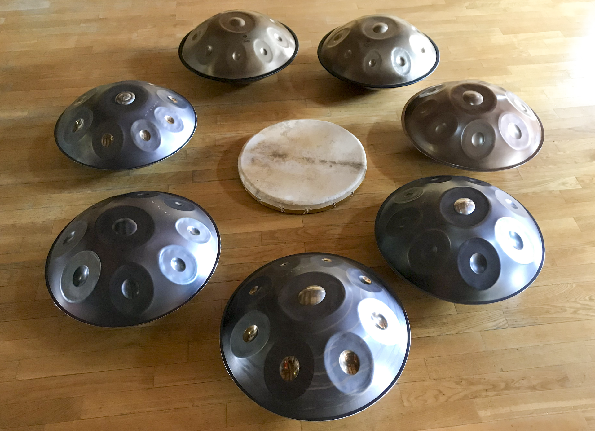 Eine Gruppe von Handpans und eine Trommel liegen auf einem Holzboden.