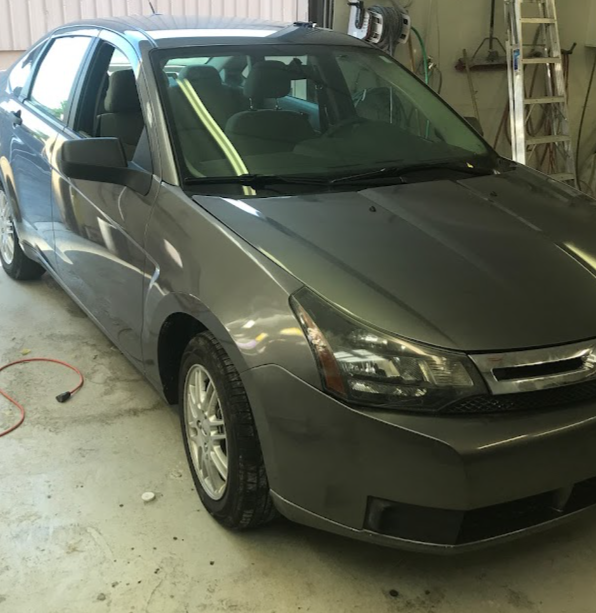 Gray sedan parked inside a garage with a ladder and tools in the background
