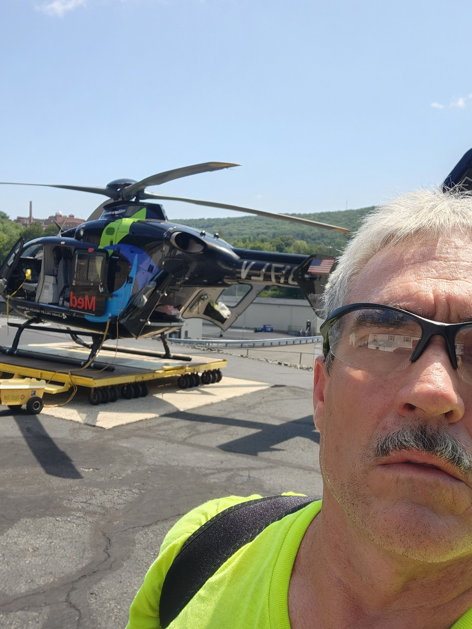 Man taking selfie with medical helicopter in background.
