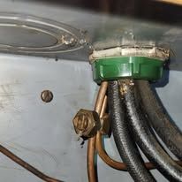 Electrical wires and connectors emerging from a metal enclosure, with a green cap and gold connector visible.
