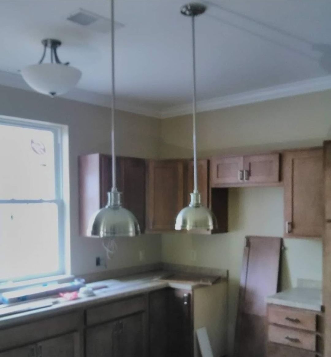 Kitchen with two pendant lights, cabinets, a window, and unfinished countertop.