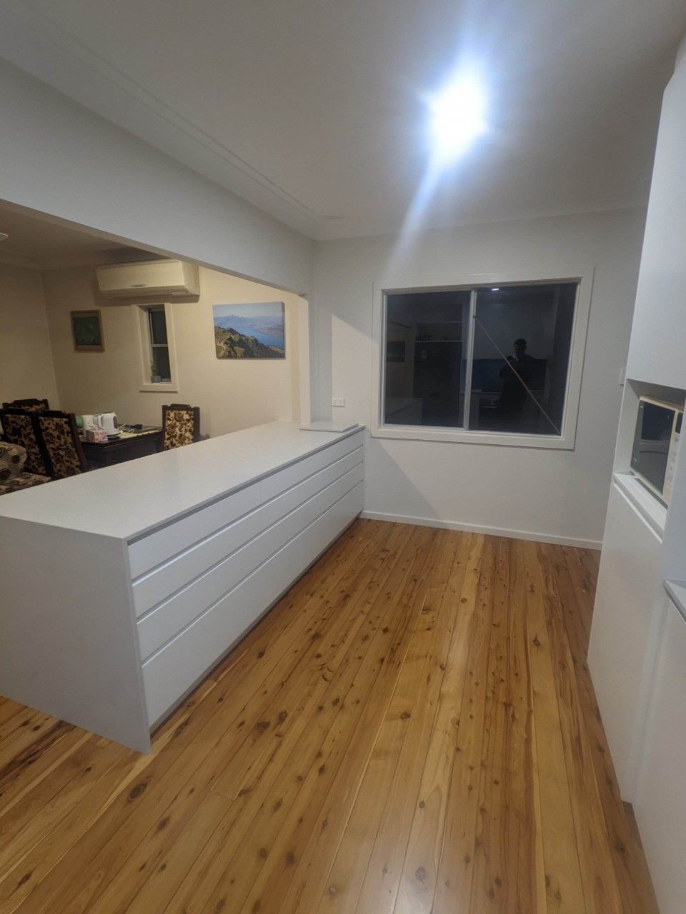 Kitchen With Wooden Floors and White Cabinets and a Large Window — Hancock Construction & Maintenance in Maitland, NSW