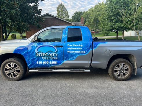 Blue and silver pickup truck with company logo parked on a street in a residential neighborhood